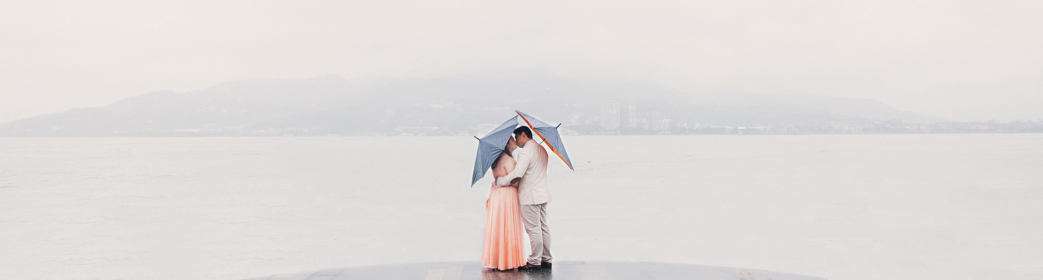 Vincent and Roshana under umbrellas in the rain overlooking Dangshui