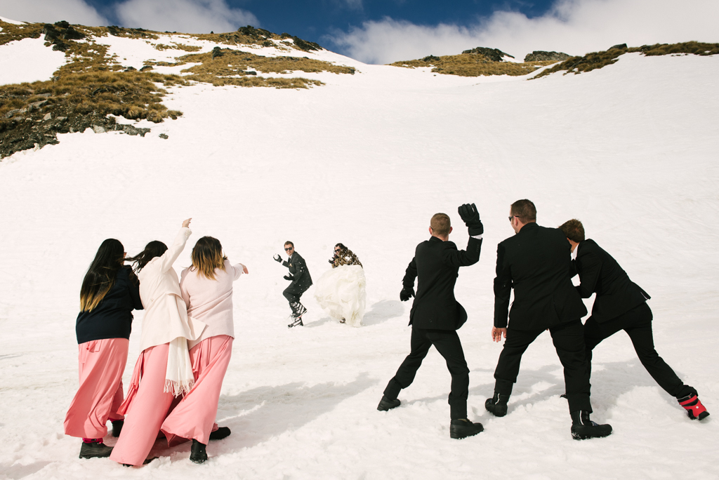 bridal party throwing snowballs at the bride and groom in Queenstown