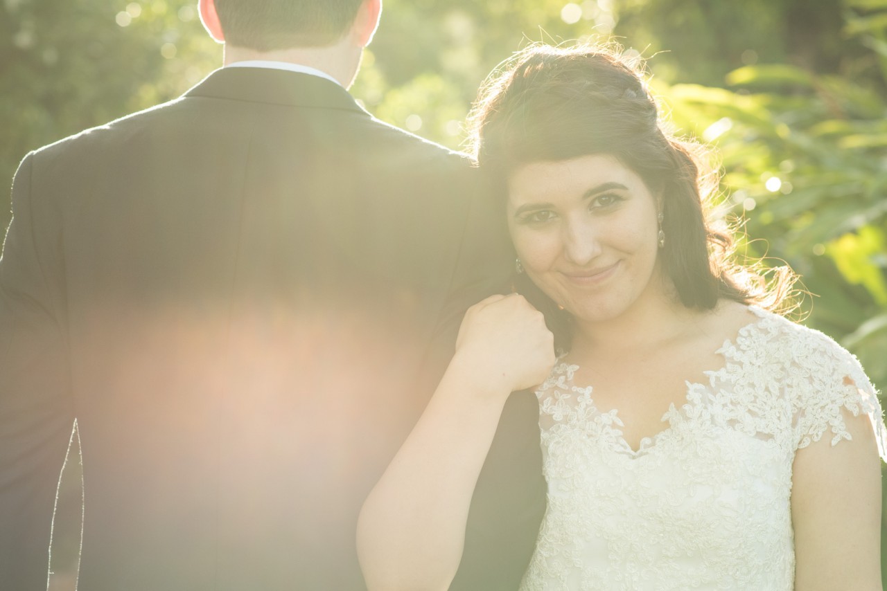 Bride leaning on groom, engulfed in sunlight
