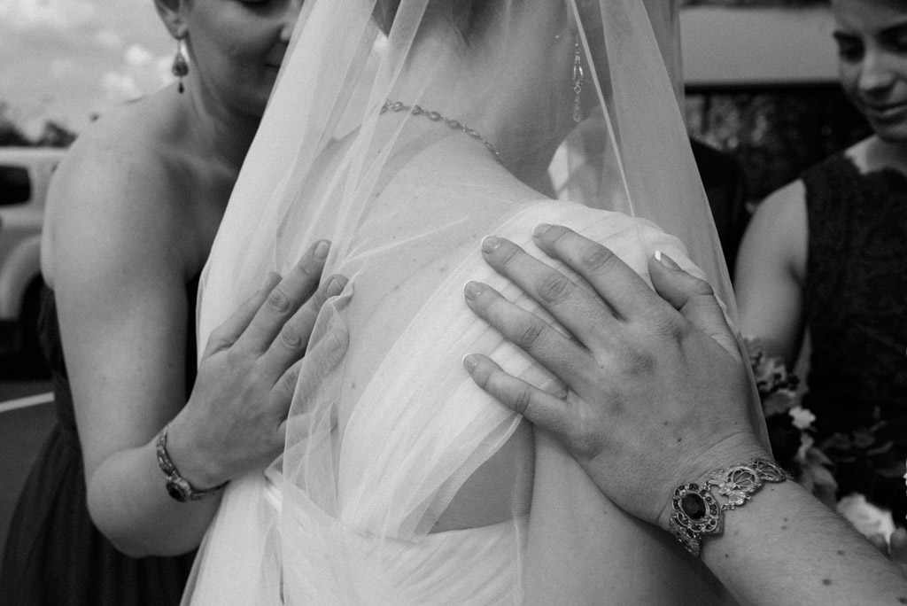 Black and white candid: hands on Michaela's shoulders in a moment of prayer