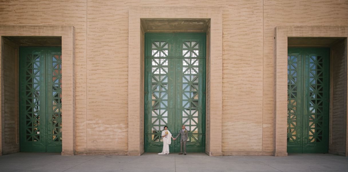 Bride and Groom standing against teal doors