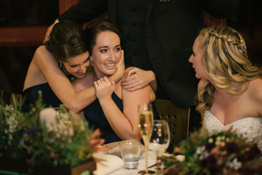 Bridesmaids hugging each other at the bridal table